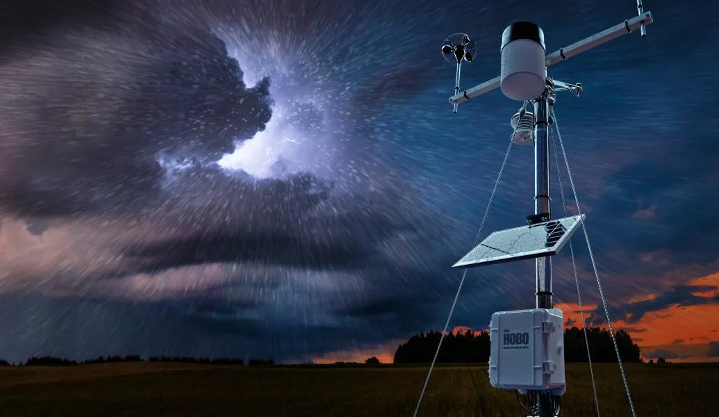 HOBO remote weather monitoring station in a field under a stormy sky